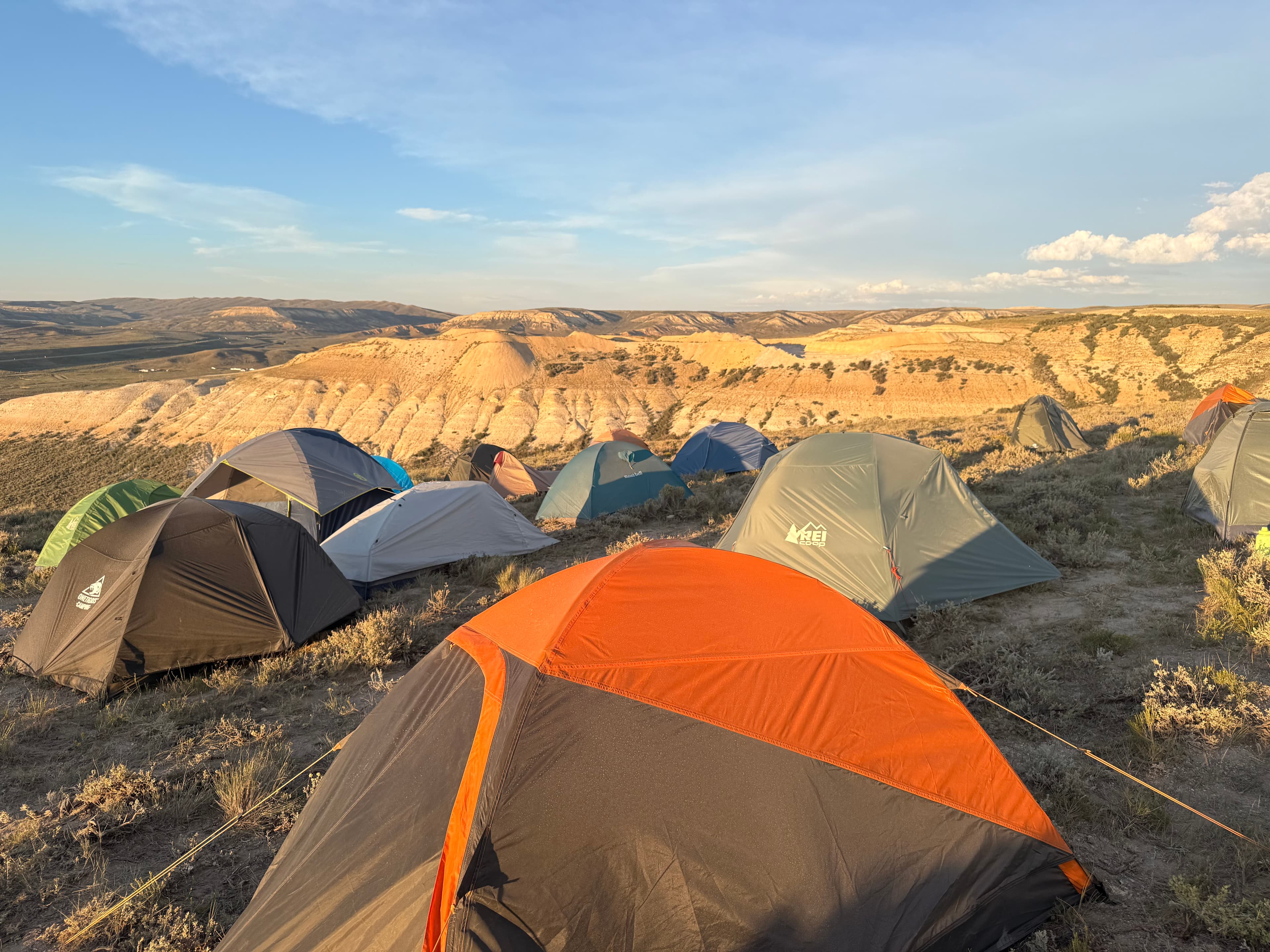 Camp tents dot the hillside under a wide Wyoming sky.