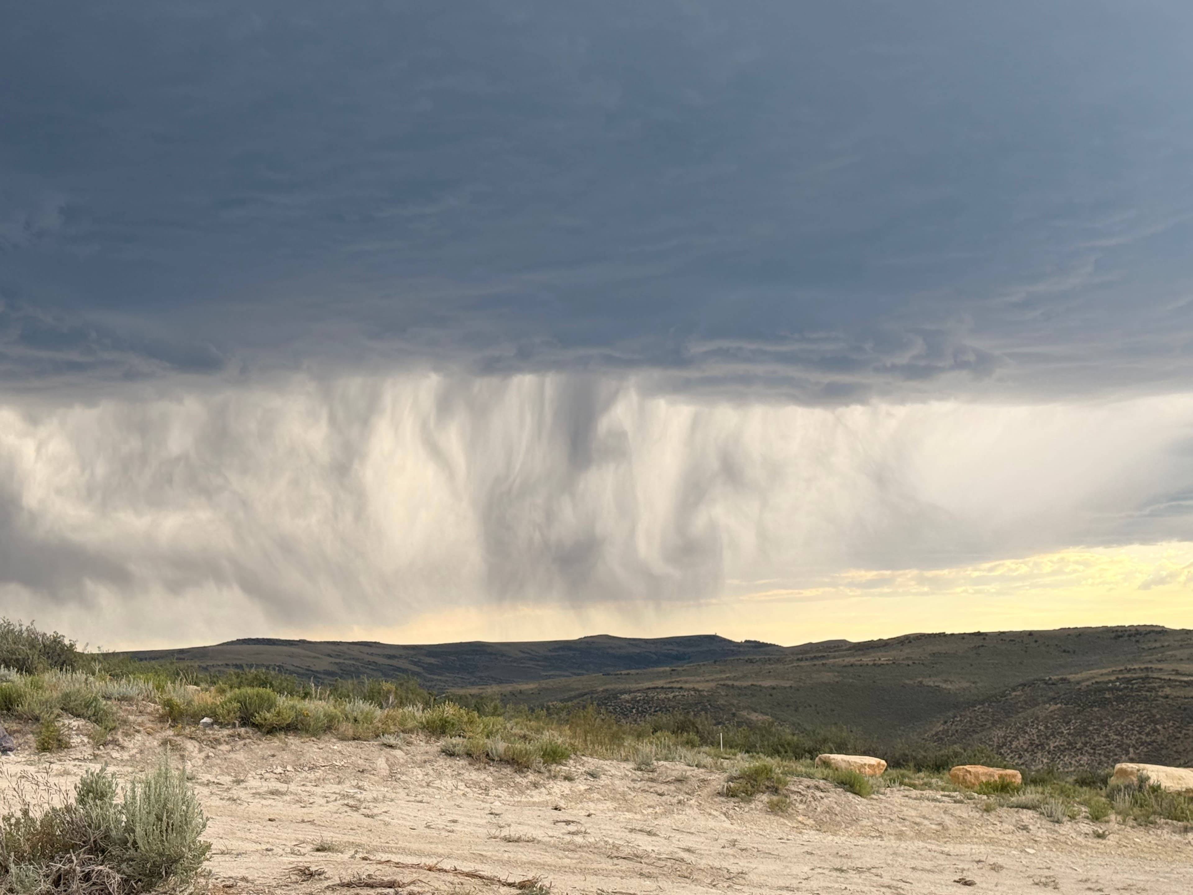 Rain curtain falling over the desert hills before the storm.