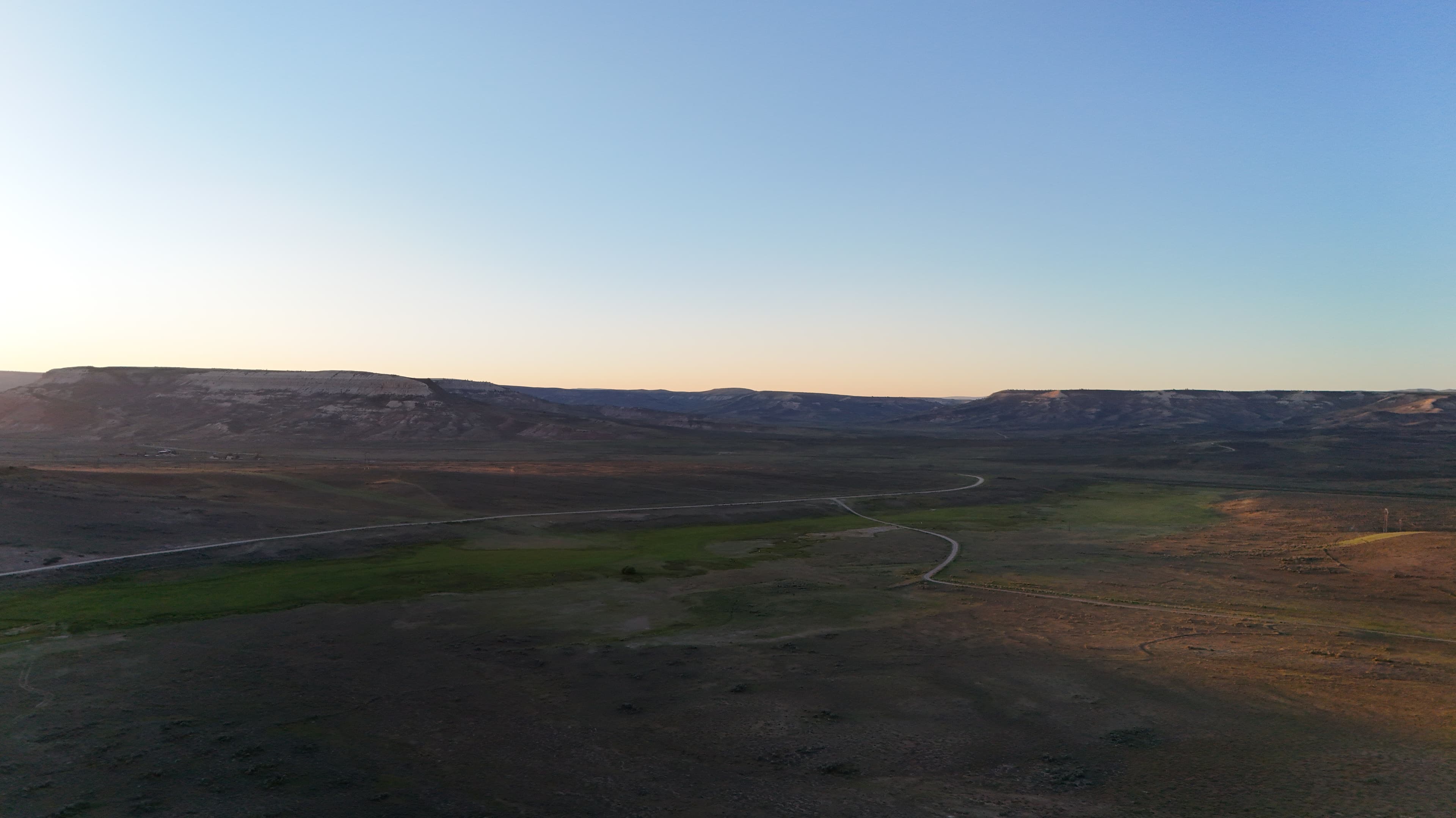 Wide view of Wyoming landscape at sunrise with distant mesas.
