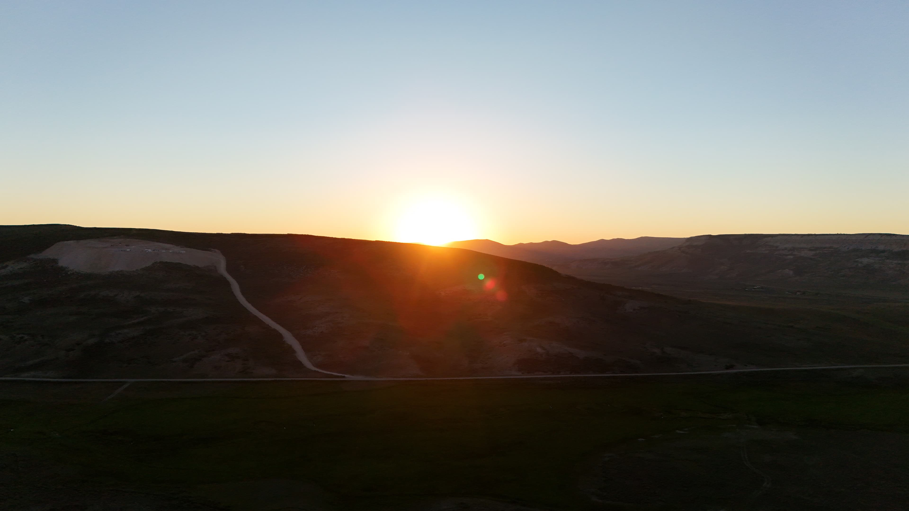 Sunrise over the quarry site with a road winding up the hill.