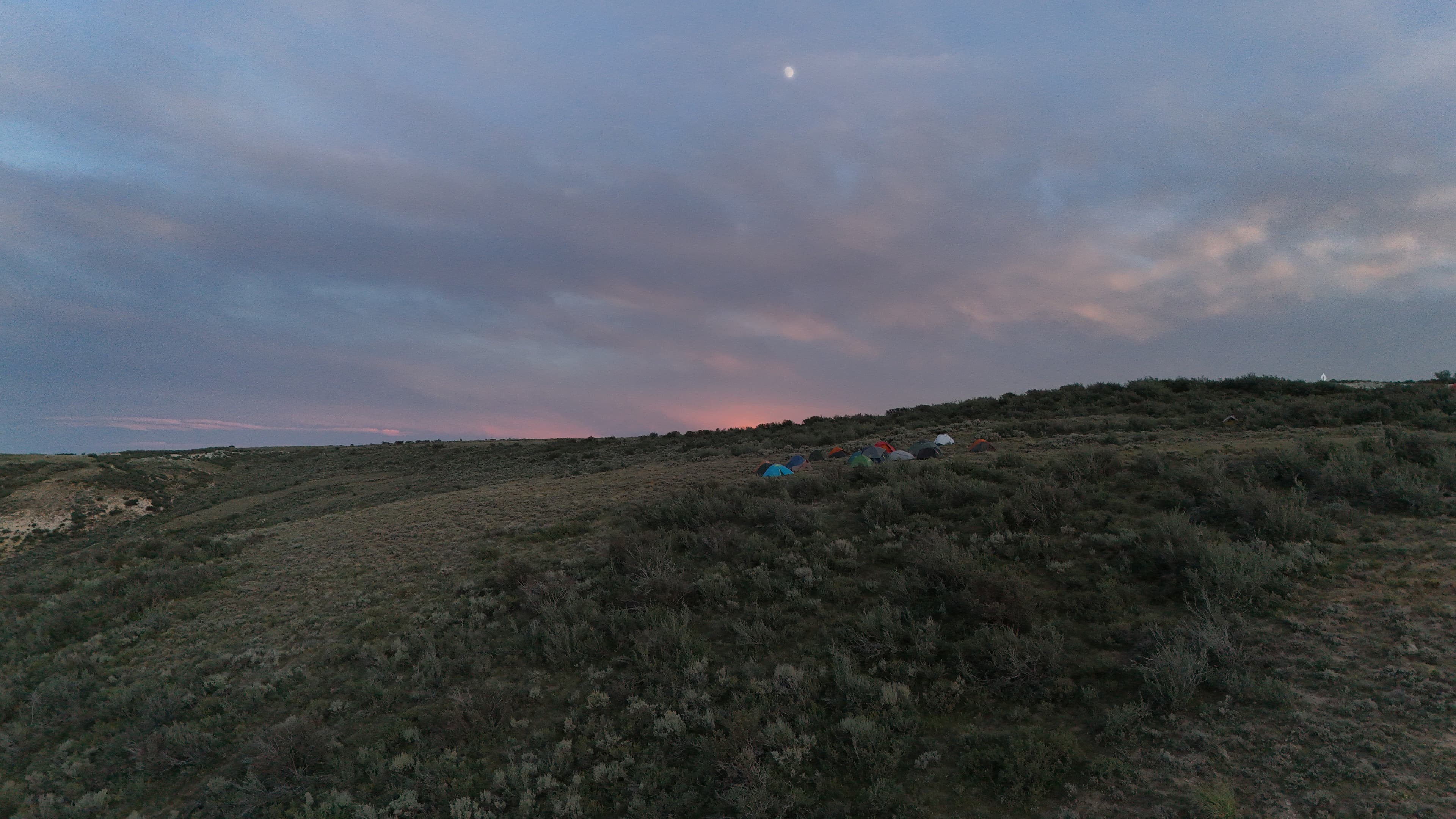 Tents on a hill under a dusky Wyoming sky.