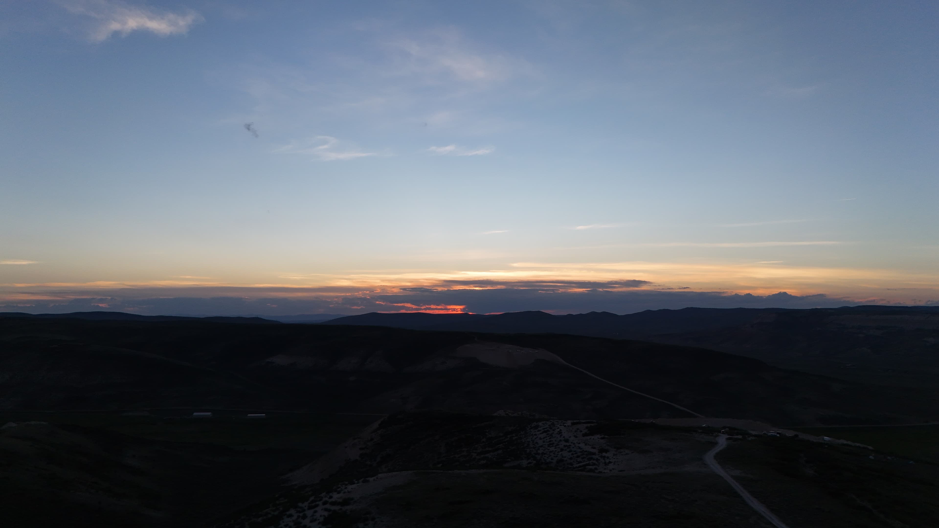 Sunset over the dig site with faint camp lights below.