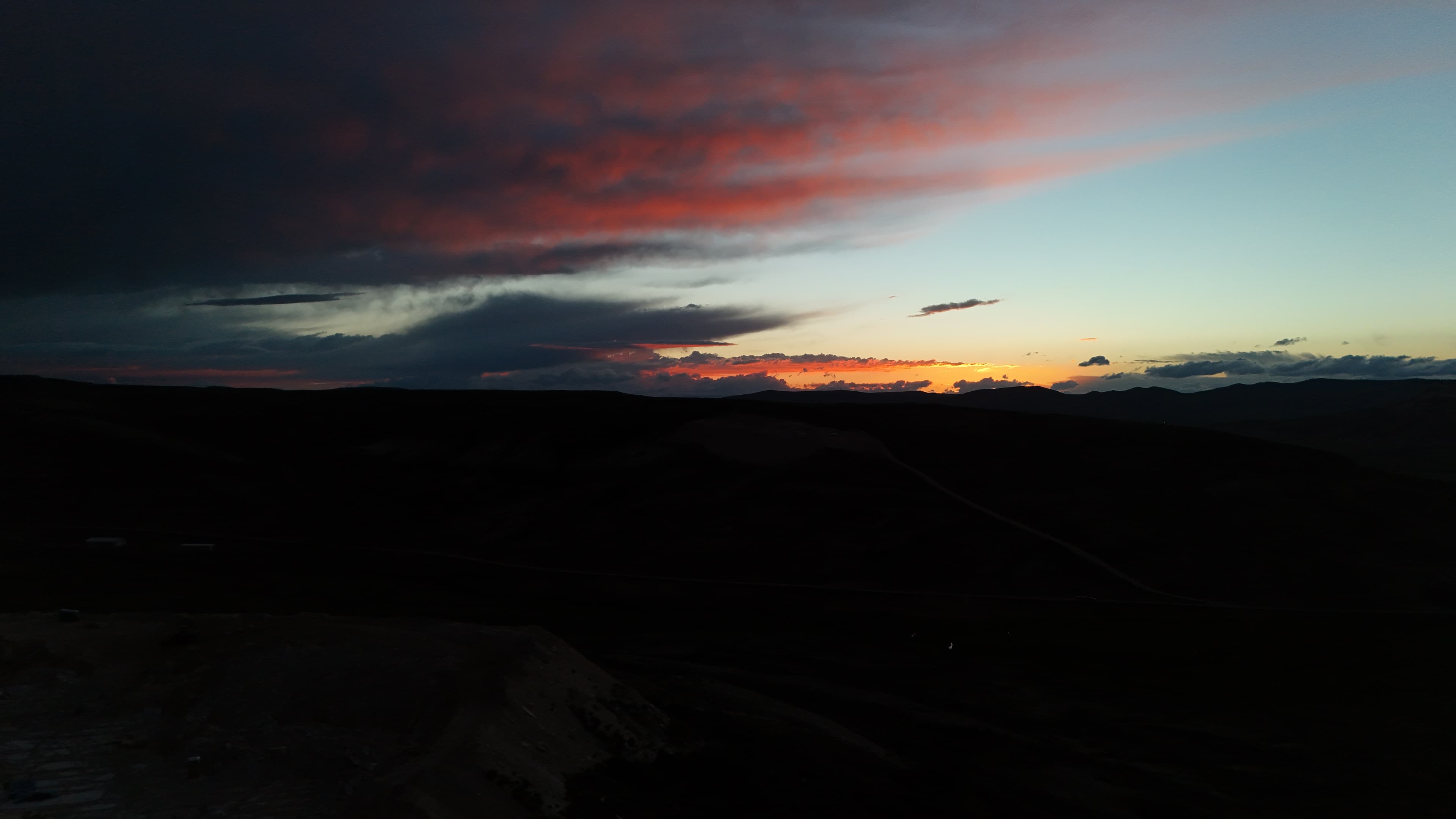 Pink and orange clouds streak across a dark Wyoming sky at sunset.
