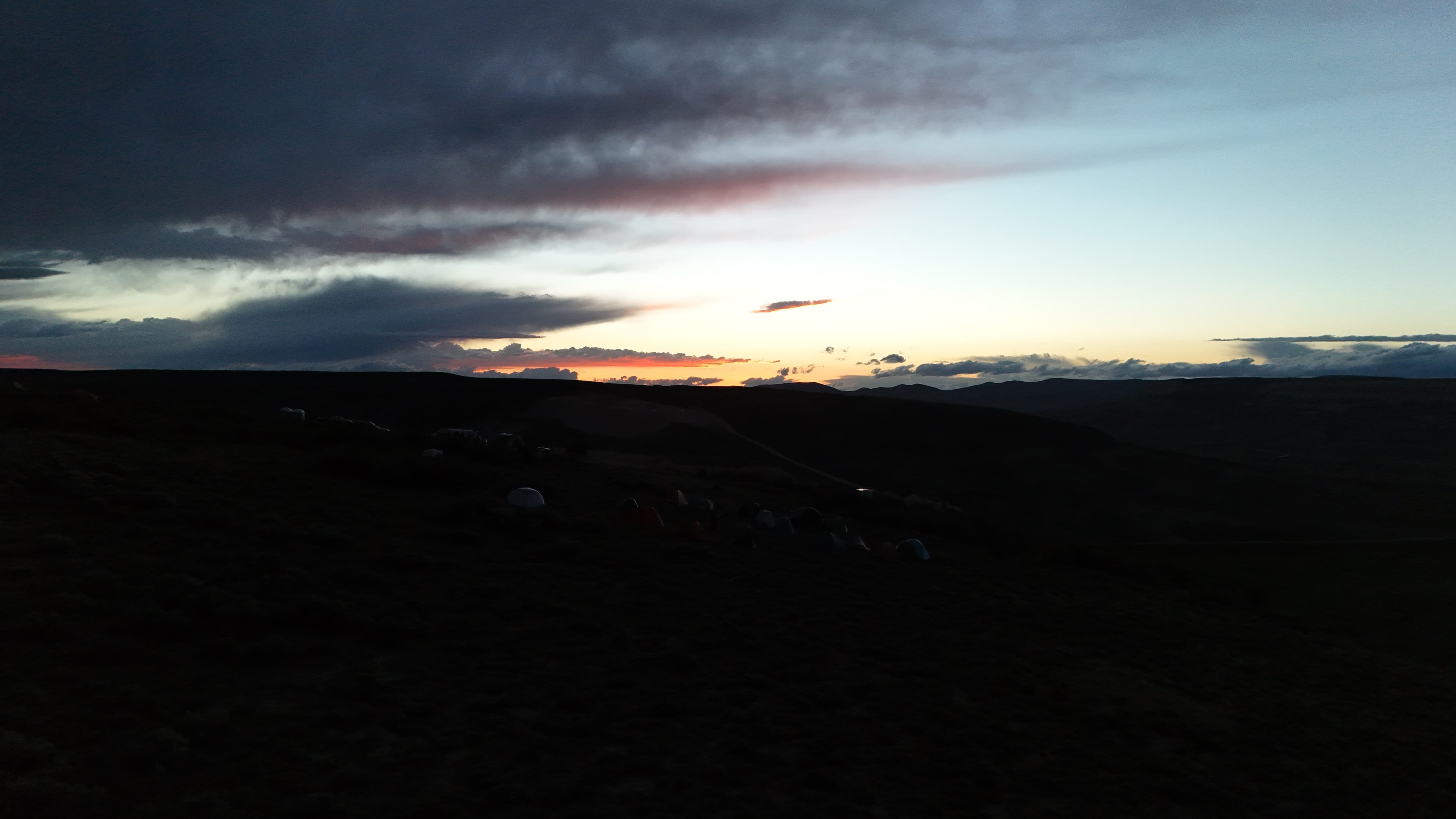 Camp tents under a dramatic Wyoming sky at sunset.
