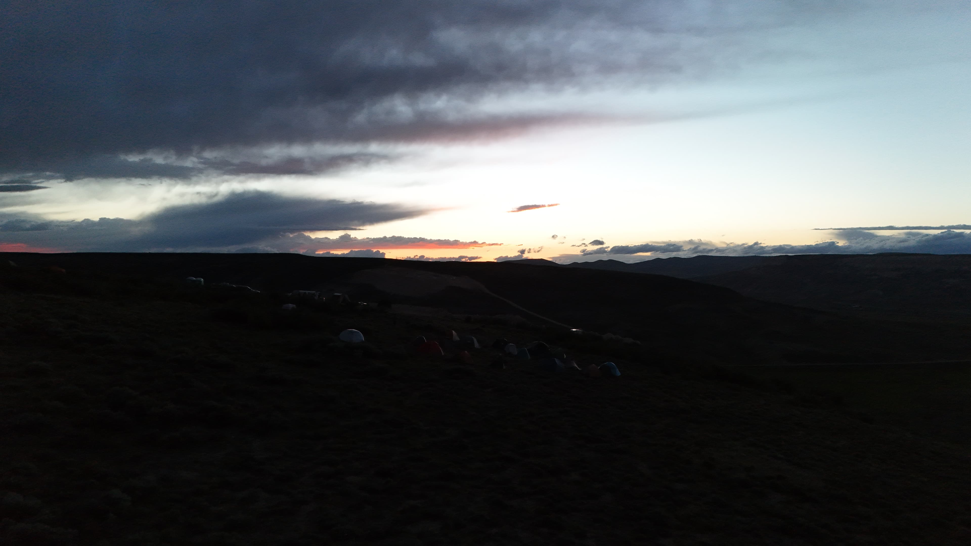 Camp tents under a dramatic Wyoming sunset sky.