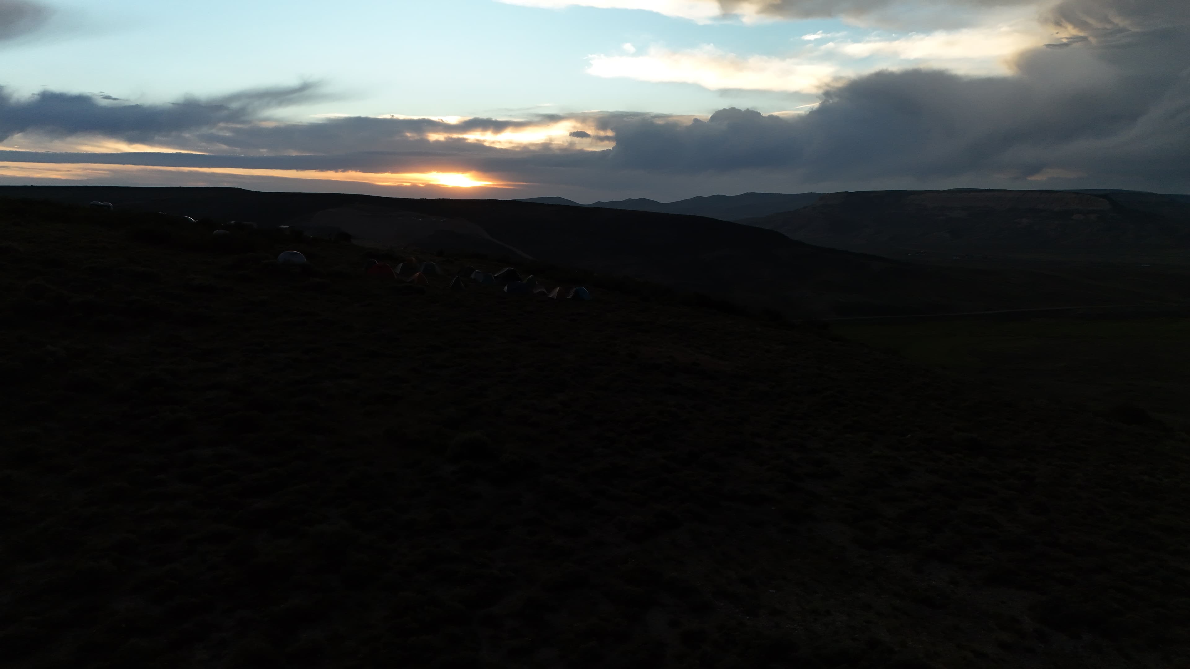 Tents dot the hillside as the sun sets over Wyoming.