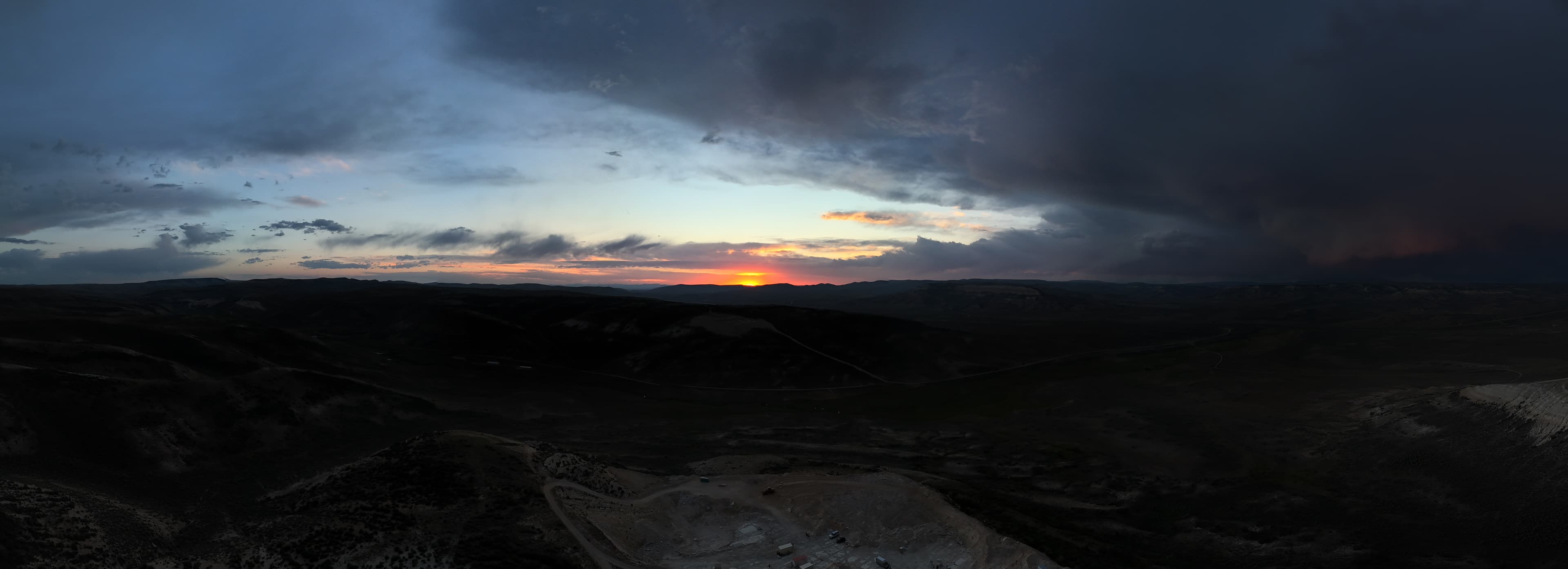 Sunset over the hills with a quarry in the foreground.