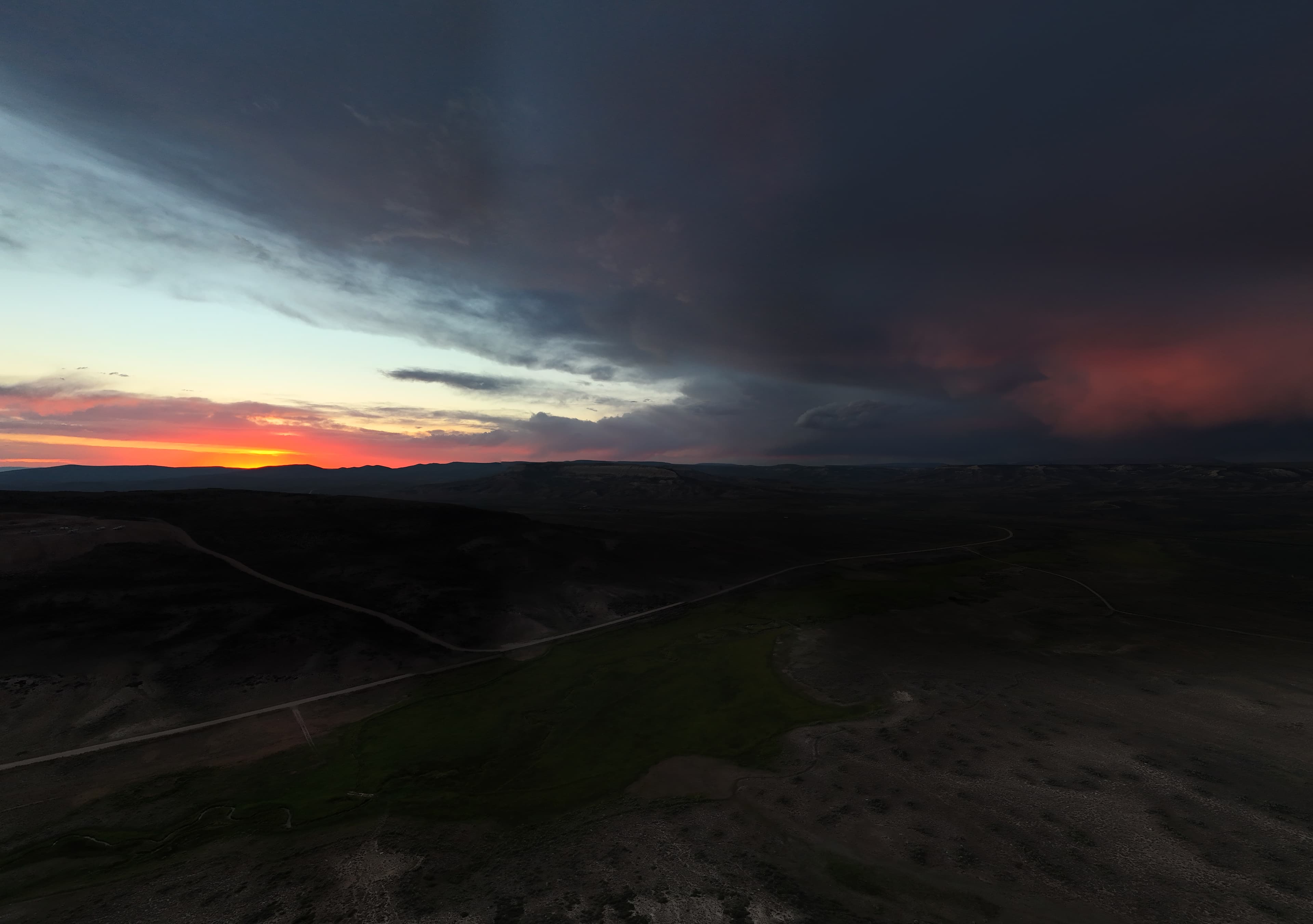 Dramatic Wyoming sunset over rolling hills and dusty roads.