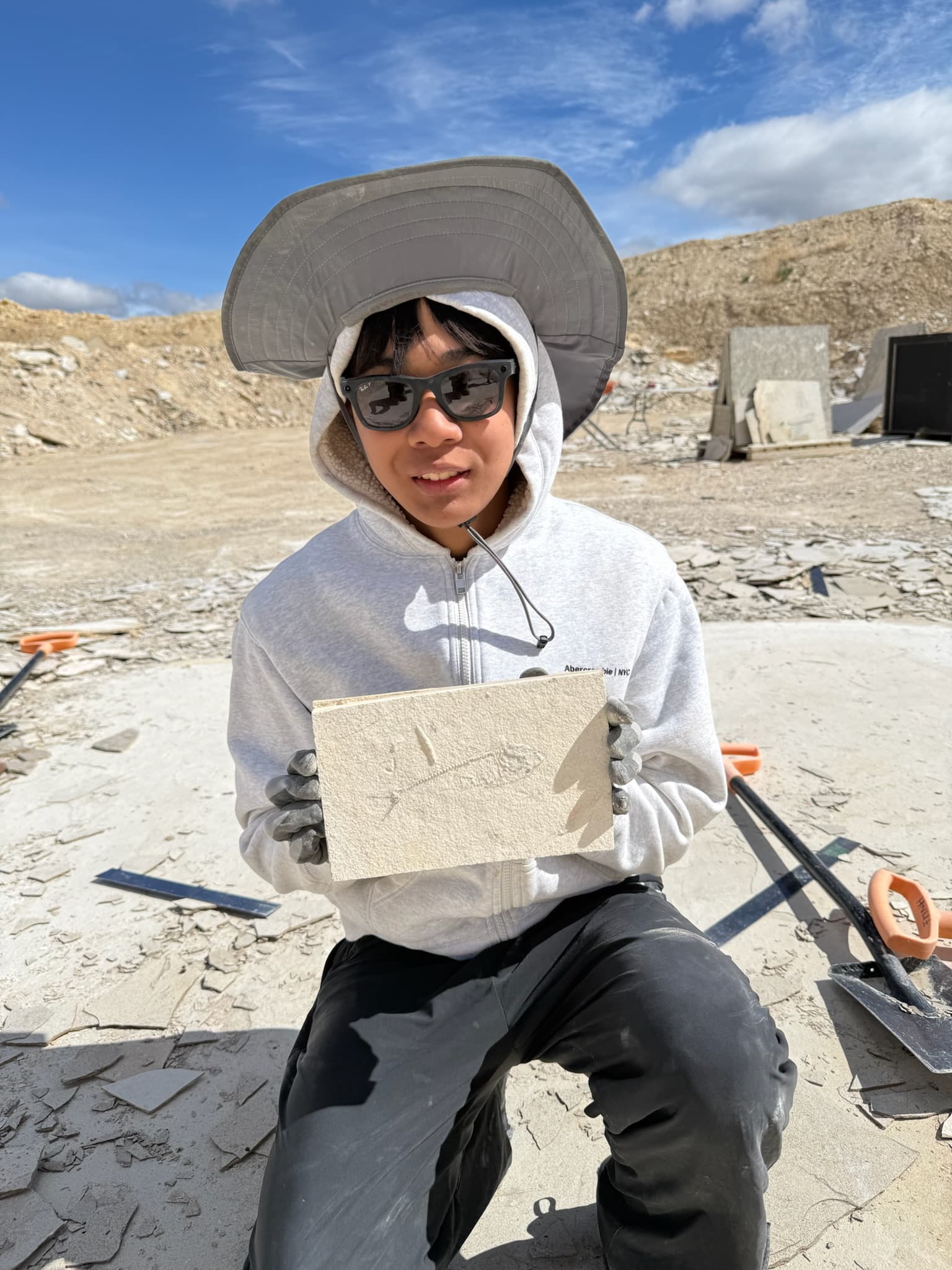 Timmy Li at In Stone Fossils Quarry holding a fish fossil in limestone